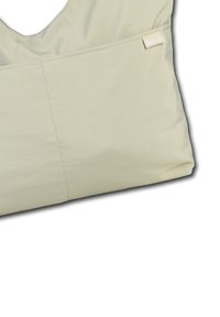 Lichtbeige stoffen tas met een gladde textuur, voorzien van een grote zak en een klein etiket met de tekst "Bench." Rondom de bovenkant met een asymmetrische vorm.