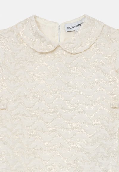 Kermansignen mekko, jossa on kelaava aaltokuosi, pyöreä kaulus ja takana vetoketjukiinnitys. Materiaalissa on hieno kiilto.