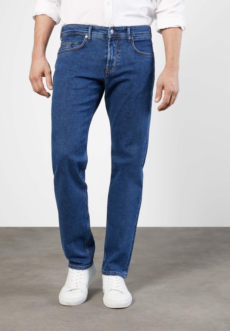 Blue denim jeans with a straight fit, five-pocket design, contrasting stitching, and a classic button closure, paired with white sneakers.