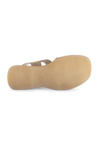 Semelle de sandale beige avec grip texturé, présentant une forme arrondie et un nom de marque gravé. Matériau lisse, semblable au caoutchouc.