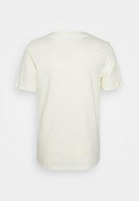 Kostee lyhyt hiha, pyöreä kaula-aukko vaalean kerma värissä. Valmistettu pehmeästä puuvillasta, jossa on sileä pinta eikä näkyviä kuvioita tai grafiikoita.