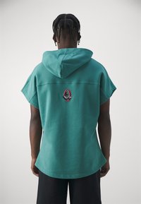 Felpa con cappuccio a maniche corte in teal, caratterizzata da un orlo arrotondato e un logo ricamato in colori a contrasto sul retro.