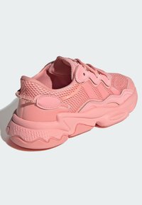 Sneaker atletica rosa con tomaia in mesh, suola in gomma testurizzata e design a strati. Presenta lacci abbinati e dettagli arrotondati.