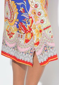 Bunt gemustertes Kleid mit verschiedenen Designs in Blau, Rot, Gelb und Pink. Enthält florale Motive, detaillierte Ränder und einen seitlichen Schlitz.