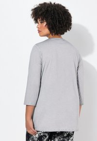 Graues Langarm-T-Shirt aus weichem Stoff, mit lockerer Passform und rundem Ausschnitt, von hinten gezeigt.