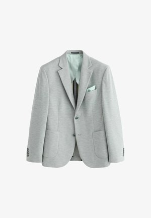 Heledad hallikas bleiser, millel on lõikeservad, kaks esist koosolekute ja nööbid mansettide peal. Sisemine vooder on piparmündiroheline ja seal on sobiv taskurätik.