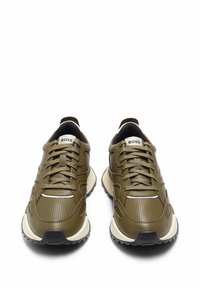 Olive green athletic sneakers with textured leather, lace-up design, white accents, and a black rubber sole. Logo on the tongue.