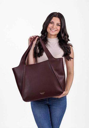 Burgundská kožená taška přes rameno se strukturovaným tvarem, dvojitými horními uchy a decentním kovovým logem. Hladký povrch a minimalistický design.