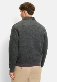 Grau melierte Wollmischjacke mit gerippten Bündchen und Saum, ausgestattet mit einem kragenlosen Halsauschnitt und einer glatten Textur. Die Rückansicht zeigt die Schulternähte und das Logodetail.