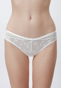 Bikini en dentelle blanche avec motif floral, taille douce et bords festonnés. Tissu semi-transparent avec des accents élastiques.