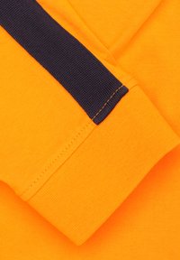 Oranje stof met een marineblauwe streep aan de manchet. Gladde textuur, met nauwkeurige stiksels en een nette afwerking. Geen zichtbare patronen.