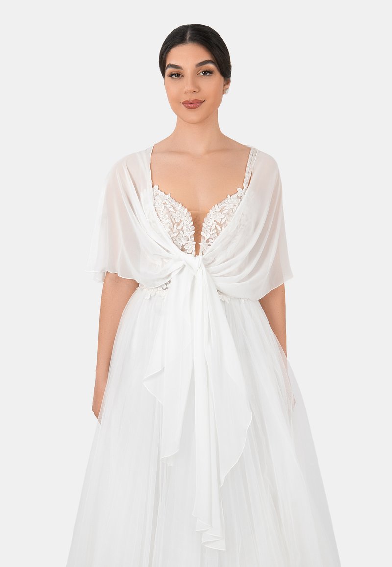 White dress featuring a sheer, draped overlay tied at the waist, with lace detailing on the bodice and a flowing, textured skirt.