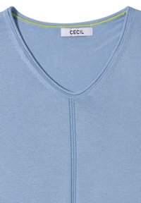 Pull bleu clair à col en V avec une couture centrale et une étiquette blanche indiquant "CECIL" à l'intérieur de l'encolure.