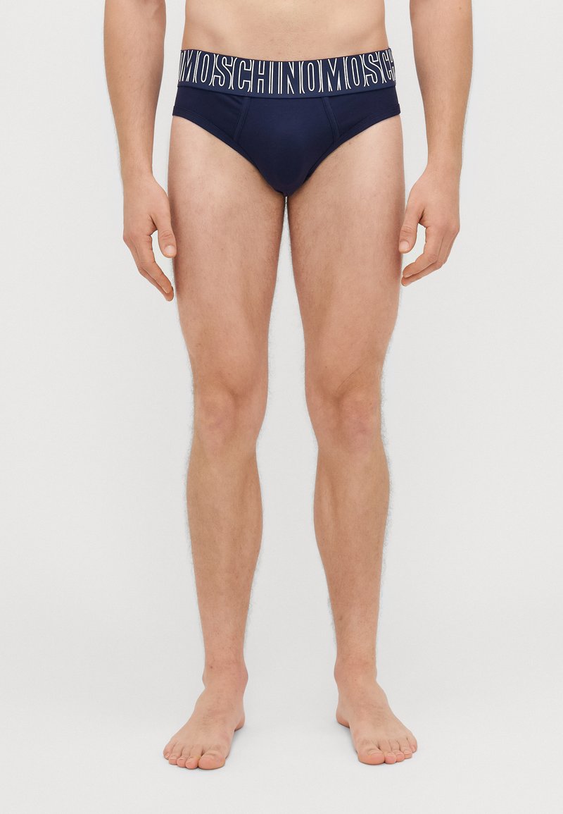 Boxers de homem azul marinho com uma faixa branca com logótipo. Apresentam um ajuste justo e um tecido suave. Sem padrões ou acentos adicionais visíveis.