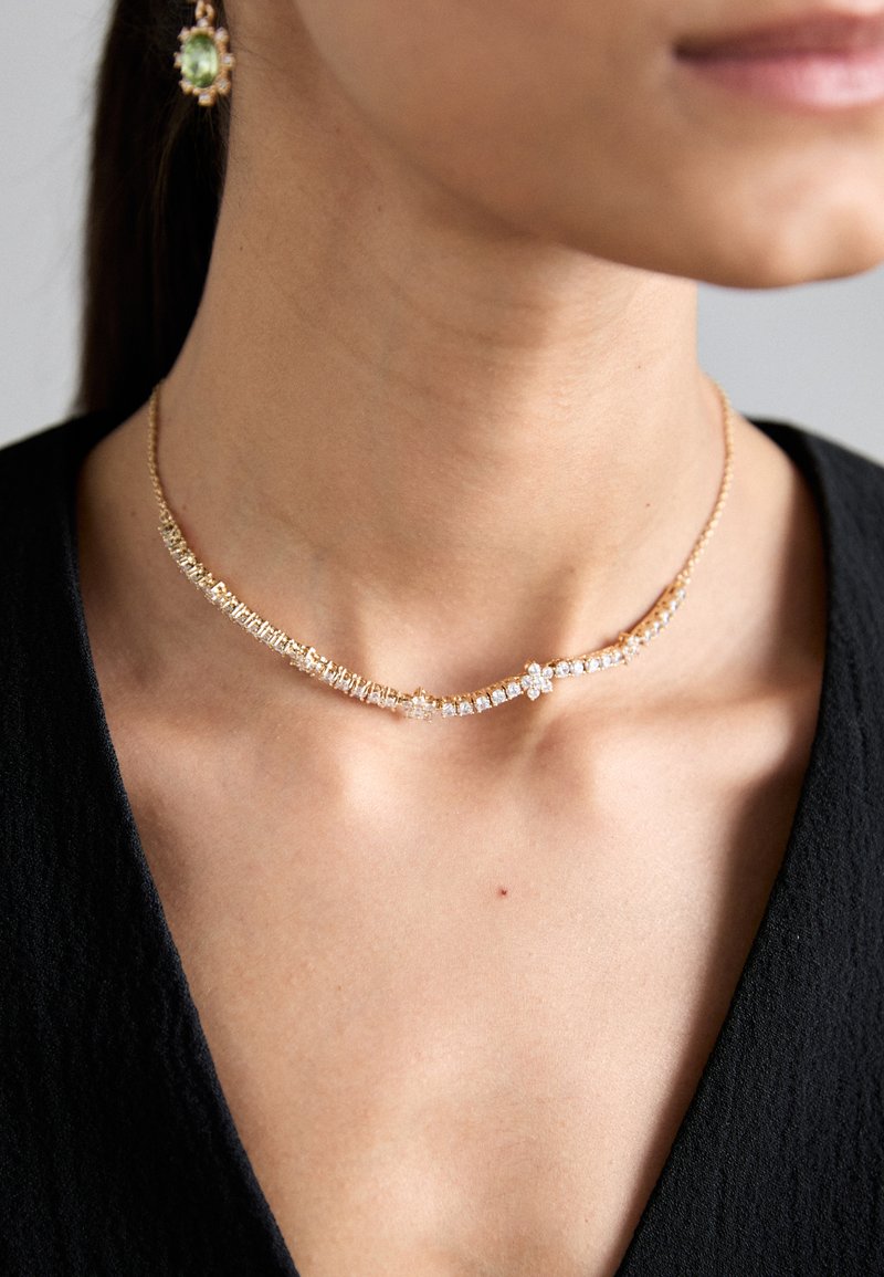Zlati choker ovratnik z izmeničnimi pravokotnimi in okroglimi prozornimi kristali, ki ima nežno verigo in poudarek v cvetličnem oblikovanju.
