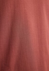 Czerwona bawełniana tkanina o gładkiej fakturze. Materiał ma subtelny wzór żebrowany, odbijający światło w delikatny sposób.