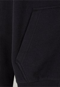 Sort sweatshirtstof med en lomme, der har en glat overflade og ribbet kant. Sømdetaljer er synlige nær lommeområdet.