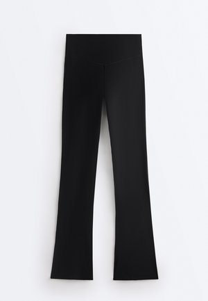 Zwarte leggings met hoge taille en brede tailleband, rechte pijp, plat weergegeven op een witte achtergrond.