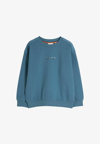 Sinine puuvillane sviiter ribatud mansettide ja kaelusega. Esiosas on tikitud "PAUL SMITH" logo. Lihtne, vabalt langev disain.