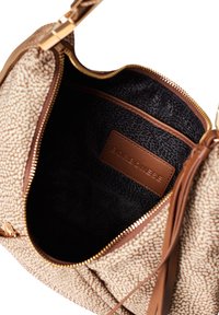 Beige Handtasche mit einer strukturierten, gepunkteten Außenseite, Reißverschluss und einem schwarzen gemusterten Innenraum. Enthält eine braune Lederbranding innen.