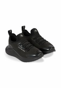 Scarpe da ginnastica nere in tessuto a rete e materiale sintetico liscio. Caratteristiche includono lacci piatti, colletto imbottito e un marchio discreto sul lato.
