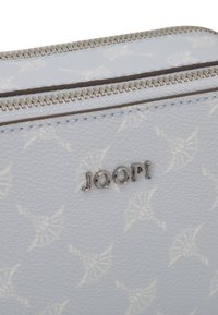 Portafoglio sintetico blu chiaro, strutturato e con un motivo sottile, dotato di chiusura a zip argentata e del logo in rilievo "JOOP!" in argento.