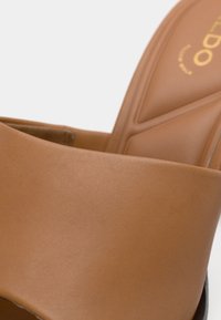 Smaragda krāsas ādas papēža sandaļi ar gludu, matētu apdari. Platām siksnām, mīkstināta zolīte un reljefā iespiests logotips uz pēdas zolītes.