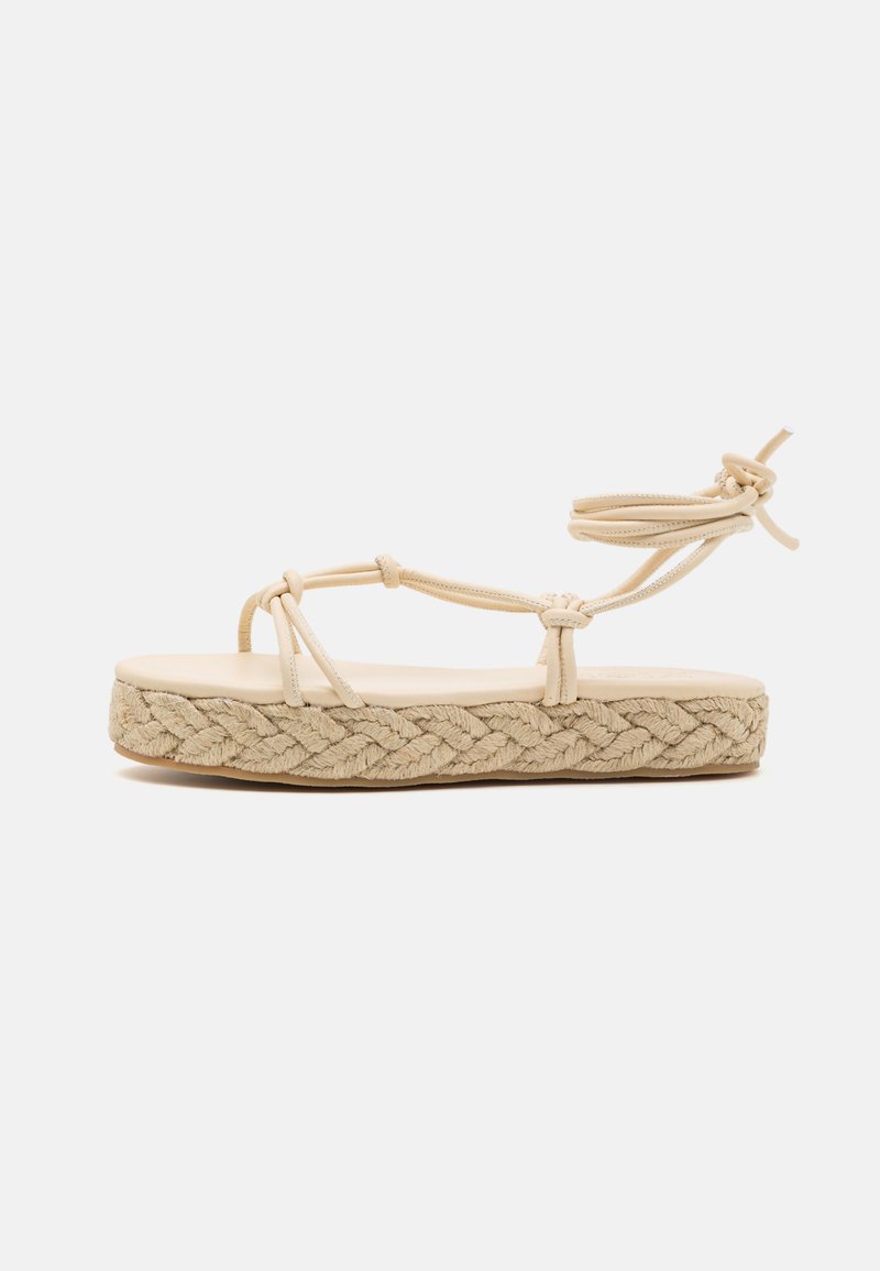 Sandal espadrille beige con suola in juta intrecciata, caratterizzata da diverse cinghie sottili e un dettaglio annodato alla caviglia per una vestibilità sicura.