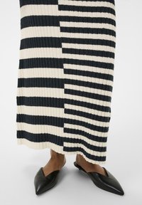 Ribota, gara svārki ar mainīgām melnām un krēmkrāsām horizontālām svītrām. Apvienoti ar melniem smailiem zābakiem.