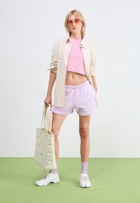 Light beige striped button-up shirt, pink cropped tank top, lavender shorts, white sneakers, and a quilted cream tote bag. Smooth textures.
