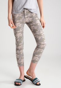 Kameleontmönstrade skinny jeans i ljusgrått och grönt, med smal passform och ankellängd, parat med platta sandaler.