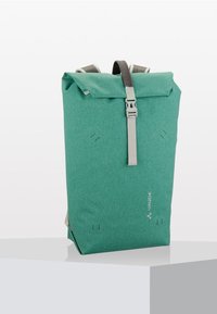 Sac à dos à rabat en teal fabriqué en tissu texturé, doté de bretelles grises et d'une boucle. Design simple avec un branding subtil et des détails de couture visibles.