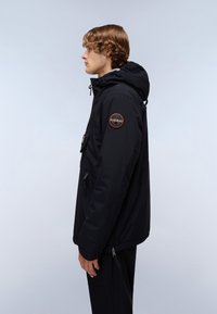 Black waterproof jacket with a hood, zippered pockets, patch on the sleeve, and a smooth texture. Side view showcasing the design and fit.