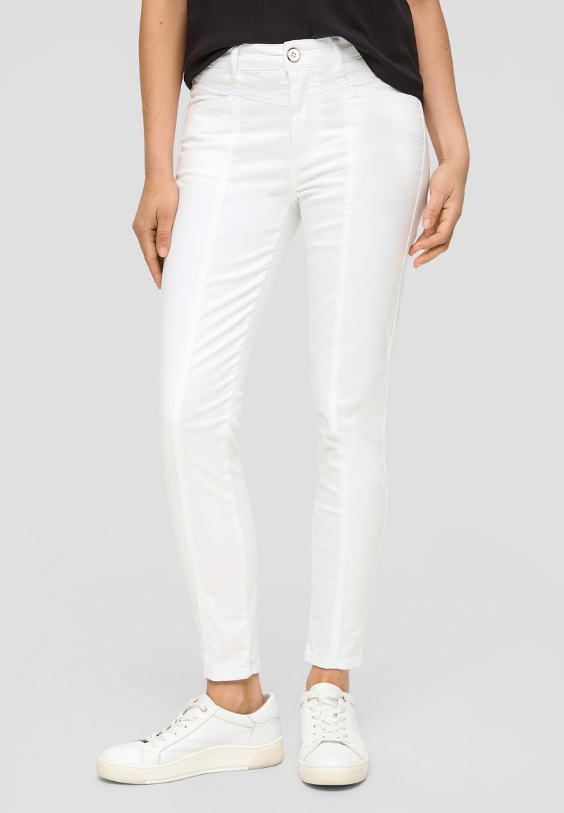 Weiße Skinny-Jeans aus einem glatten Baumwollmix, Slim-Fit, mit subtilen Seitennähten und einem Knopfverschluss an der Taille. Kombiniert mit weißen Sneakers.