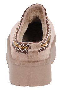 Beige slipsko i mjukt suède, med en pluffig foder, dekorativ sömnad i brunt och gult samt en strukturerad gummisula.