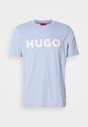 Hele sinine puuvillane T-särk, millel on ümmargune kaelus ja lühikesed varrukad. Ees on suur valge tekst "HUGO". Sile tekstuur.