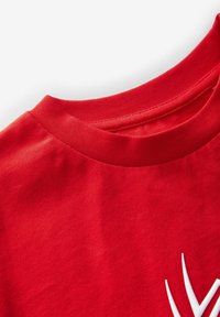 Rød bomulds T-shirt med rund halsudskæring, glat tekstur og et hvidt grafisk design på forsiden. Accenter inkluderer en ribbet krave.