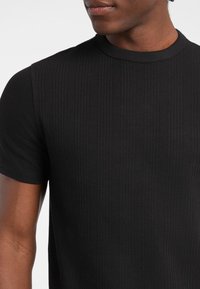 Czarny, prążkowany, krótkoskrzydły t-shirt z okrągłym dekoltem, charakteryzujący się gładką teksturą i subtelnymi detalami w szwach.