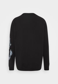 Pull noir à manches longues avec un motif de dragon blanc partiellement visible sur la manche droite, vu de dos.