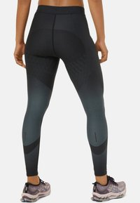 Leggings taille haute en dégradé de gris foncé avec des motifs géométriques. Fabriqués en tissu extensible, dotés d'accents réfléchissants et d'une texture lisse.