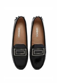 Mocassins en cuir noir avec une semelle plate, présentant un accent rectangulaire en ton doré et des coutures complexes le long des bords. L'intérieur est beige.