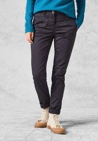 Chinos marine foncé avec une coupe slim, dotés de poches avant, d'un design à plat et de ourlets roulés, associés à des baskets montantes beige.