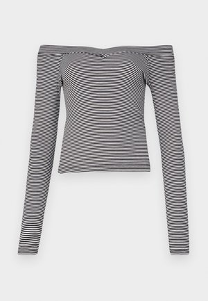 Top de manga longa com riscas pretas e brancas, off-the-shoulder, feito de tecido suave, com um design ajustado e decote estreito.
