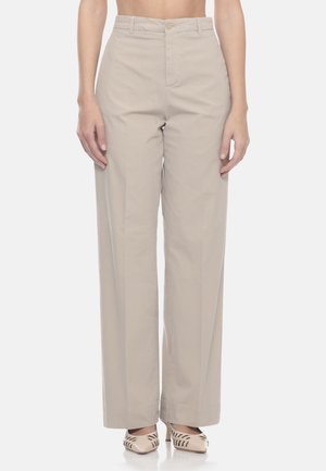 Pantaloni beige a vita alta e gamba larga indossati con décolleté beige a punta con motivi scuri a foglia.