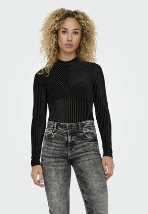 Body nero a maniche lunghe con texture a righe verticali; design aderente con collo alto. Indossato con jeans neri in denim a vita alta.