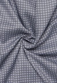 Tessuto intrecciato con un motivo geometrico di esagoni in blu navy e bianco. Texture liscia con una leggera lucentezza.