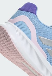Chaussure de sport bleu clair avec des accents violets et roses. Tige en maille respirante, semelle intermédiaire texturée et semelle extérieure en caoutchouc avec motif. Détail du logo en argent.