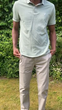 Camisa polo verde claro con un cuello en contraste y pantalones beige. La camisa tiene un corte ajustado y un logo sutil en el pecho.