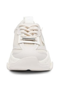 Weiße Sportsneaker aus Mesh und synthetischen Materialien, mit einer gepolsterten Sohle, flachen Schnürsenkeln und einem metallischen Emblem auf der Zunge.