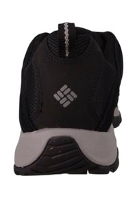 Schwarzer Sportschuh mit einem strukturierten Mesh-Obermaterial, reflexierenden Akzenten und einer hellgrauen Gummisohle mit einem gemusterten Profil.